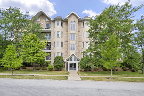 Front view of a multi-story building with balconies and trees.