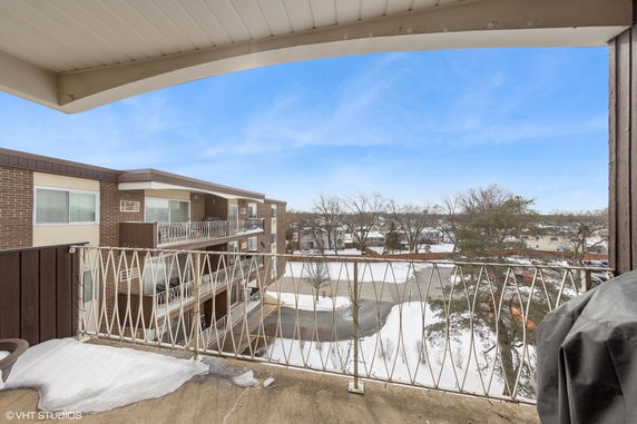 View from a balcony overlooking an apartment complex and snowy landscape.