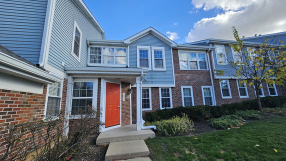Front view of a two-story townhouse with blue siding and red brick facade.