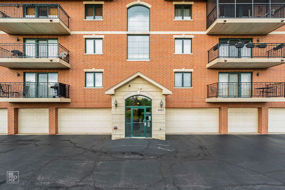Front view of a multi-story brick building with balconies and a central entrance.