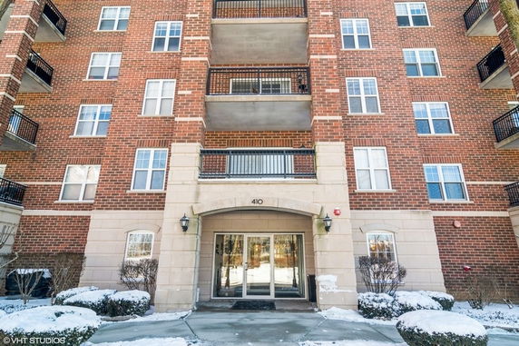 Front view of a multi-story brick building with balconies and an entrance.