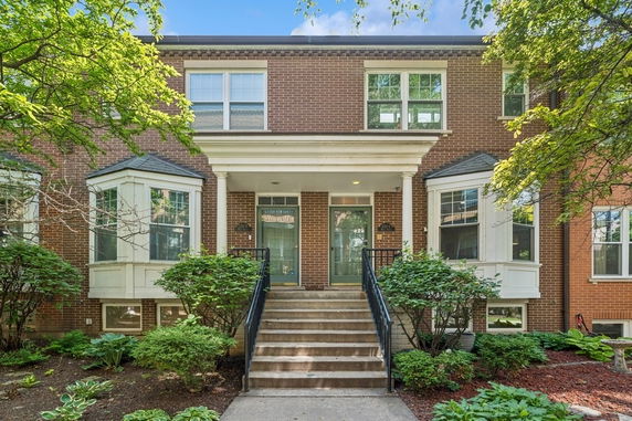 Front view of a two-story brick house with a central staircase and bay windows on either side.
