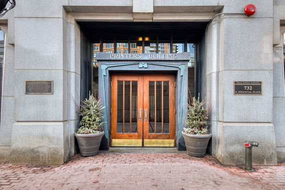 Front view of a building with a wooden double door entrance and stone facade.