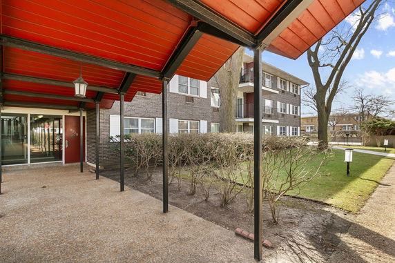 Front view of a three-story apartment building with a covered walkway.