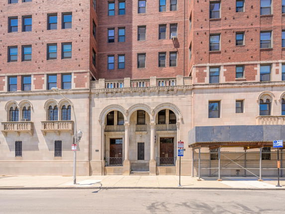Front view of a multi-story brick building with arched entryways.