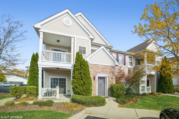 Front view of a two-story house with a balcony and brick facade.