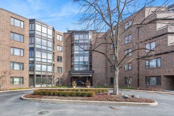 Front view of a multi-story brick building with large windows and an entrance canopy.