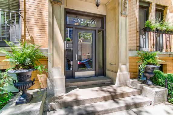 Front view of a building entrance with stone steps and decorative planters.