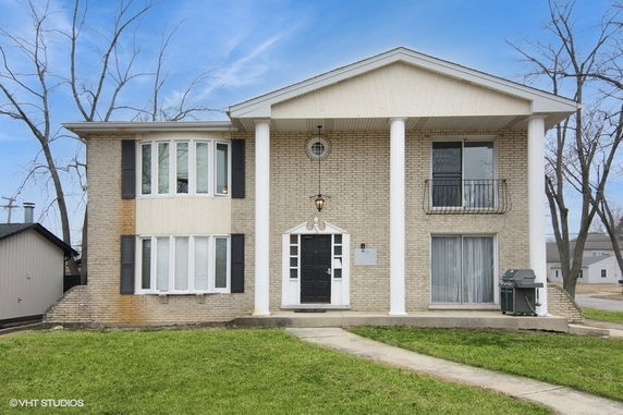 Front view of a two-story house with large pillars and a central door.