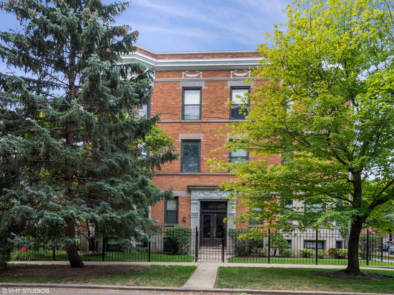 Front view of a multi-story brick building with a central entrance and windows.