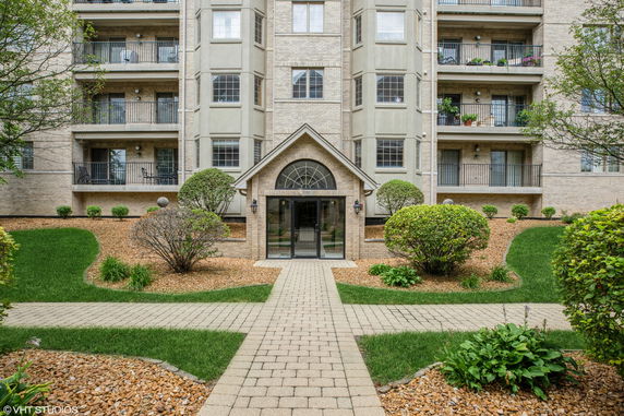 Front view of a multi-story residential building with balconies and a central entrance.