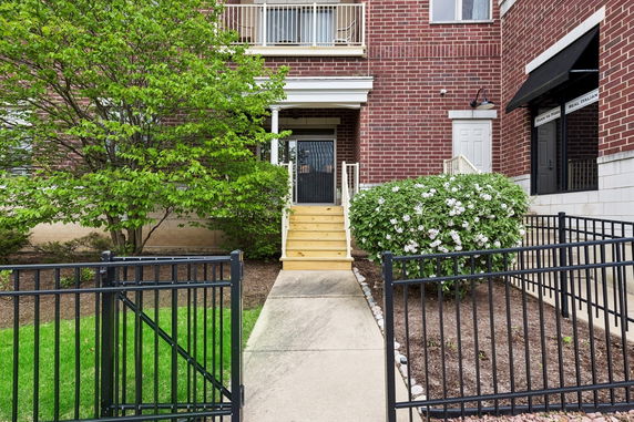 Front view of a brick building with a porch and metal gate entrance.