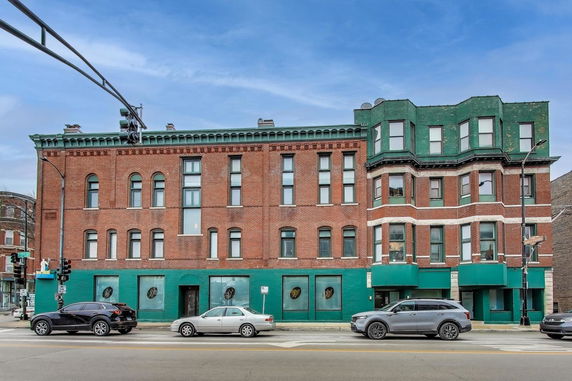 Front view of a three-story brick building with green accents and multiple windows.