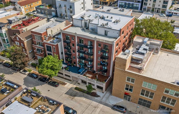 Front view of a multi-story brick building with balconies and adjacent structures.