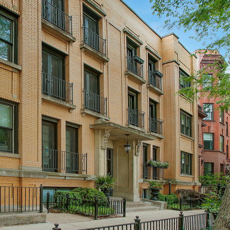 Front view of a multi-story brick building with decorative balconies and a central entrance.