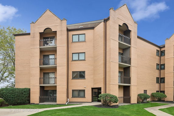 Front view of a multi-story brick apartment building with balconies.