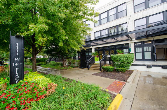 Front view of a multi-story building with black-framed windows and a covered entrance.
