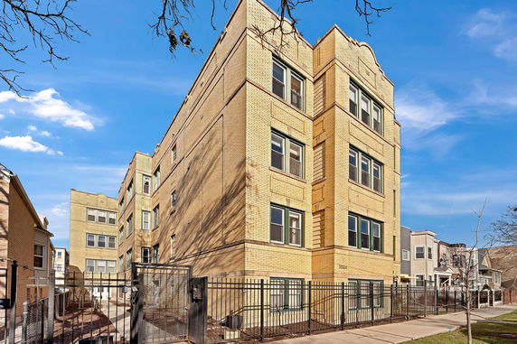 Front view of a multi-story brick apartment building with large windows.