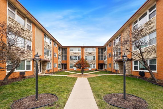 Front view of a multi-story residential building with brick and stone facade.