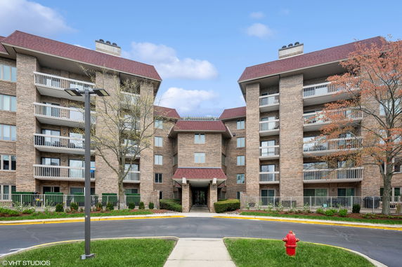 Front view of a multi-story brick apartment building with balconies.