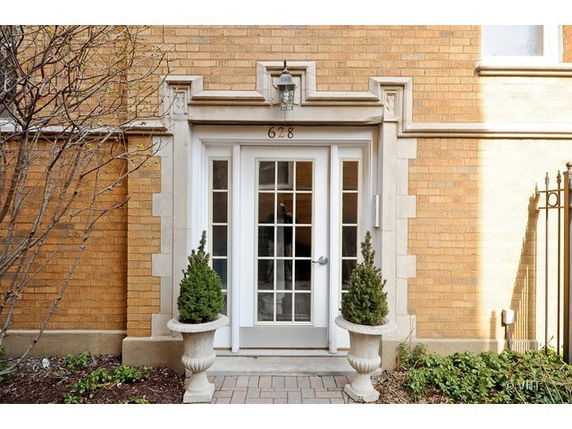 Front view of a brick building entrance with glass doors and decorative stone framing.