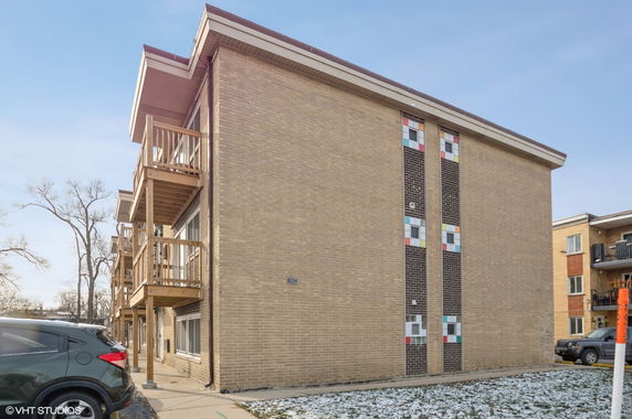 Exterior view of a multi-story brick apartment building with colorful window designs and balconies.