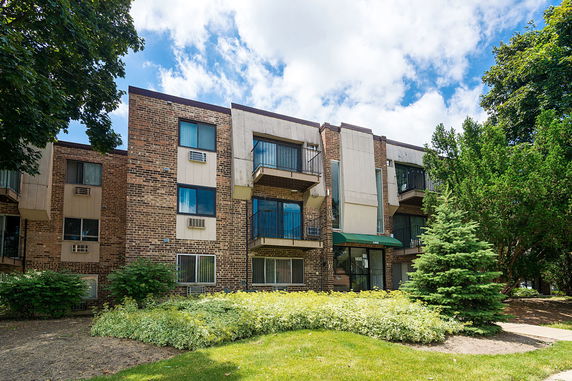 Front view of a multi-story residential building with balconies and brick facade.
