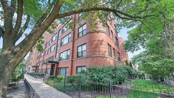 Front view of a multi-story brick building with large windows.