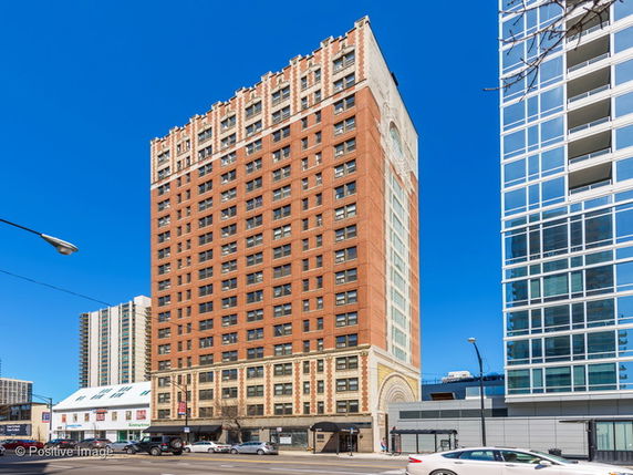 Front view of a tall multi-story building with brick facade and multiple windows.