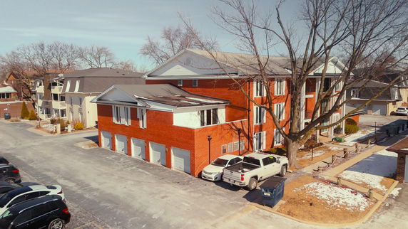 Front view of a multi-story brick apartment building with multiple garages.