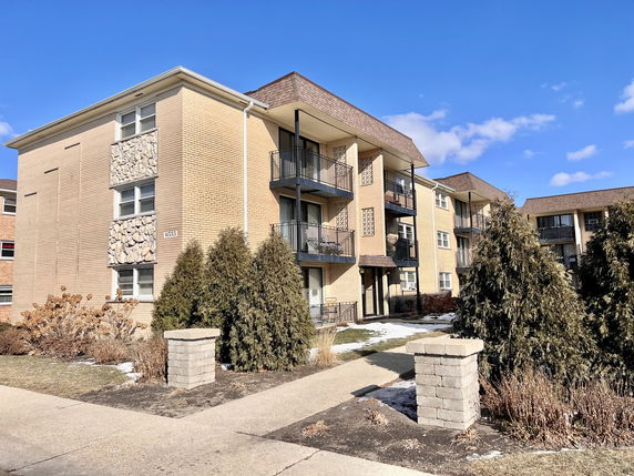 Front view of a multi-story apartment building with balconies.