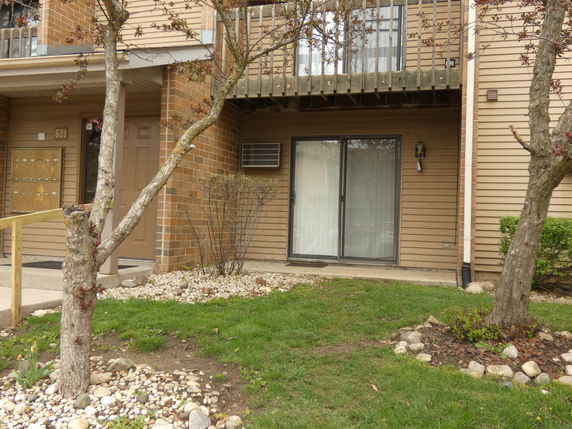 Front view of a multi-story building with sliding glass door and balcony.