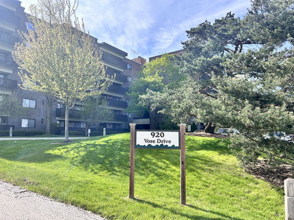 Front view of a multi-story residential building with balconies and a visible street sign labeled 920 Vose Drive.