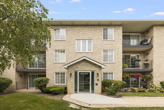 Front view of a three-story apartment building with balconies and a central entrance.