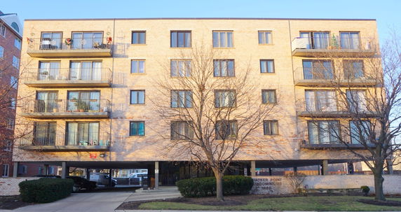 Front view of a multi-story brick apartment building with balconies.