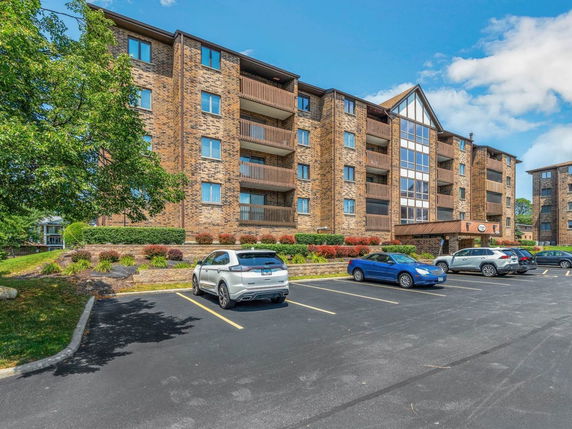 Front view of a multi-story brick apartment building with balconies.