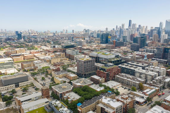 Aerial panoramic view of a cityscape with numerous buildings and a skyline in the distance.