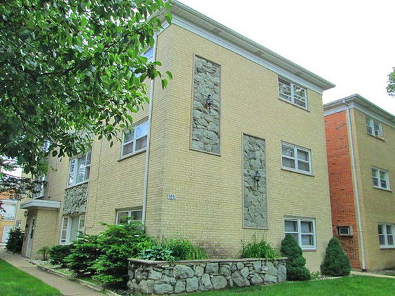 Front view of a two-story building with a brick exterior and decorative stone panels.
