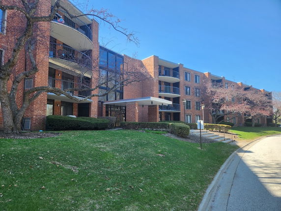 Front view of a multi-story brick apartment building with balconies.