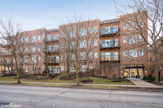 Front view of a multi-story brick building with balconies and many windows.