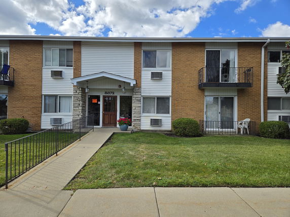 Front view of a two-story apartment building with balconies.
