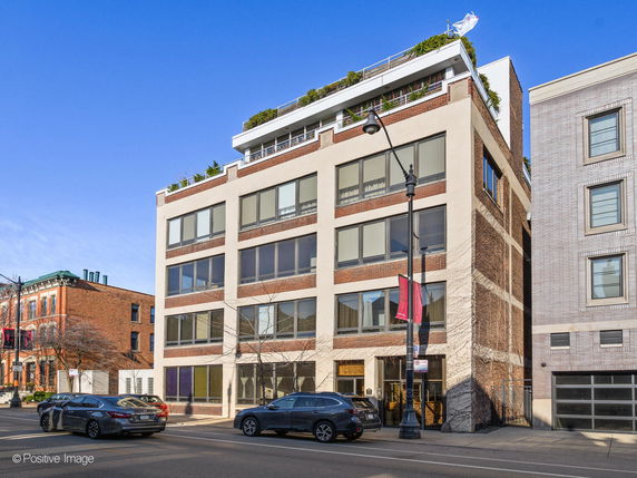 Front view of a multi-story building with large windows and a rooftop garden.