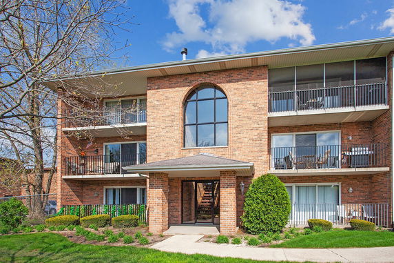 Front view of a three-story brick apartment building with balconies.
