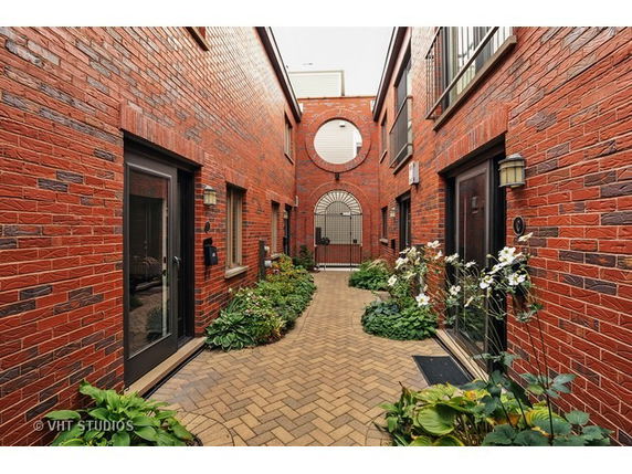 Front view of a building with brick exterior and multiple doorways along a pathway.