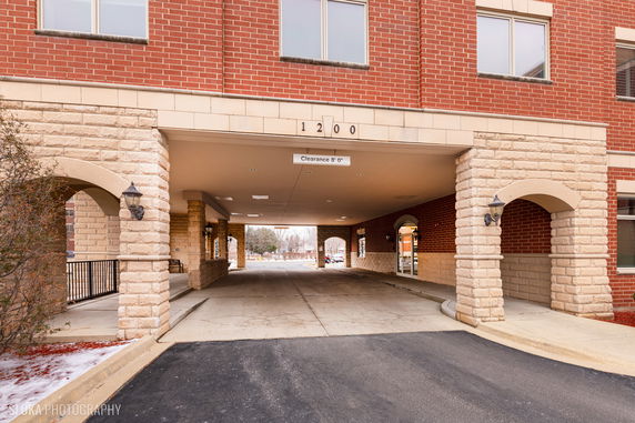 Covered parking area beneath a building with brick and stone exterior.
