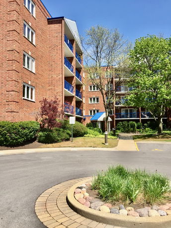 Front view of a multi-story brick apartment building with balconies.