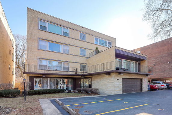 Front view of a multi-story building with a balcony and garage.