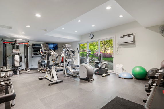 Indoor gym area with exercise equipment and weights.