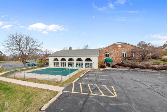 Front view of a brick building with arched windows and an adjacent swimming pool covered for the season.