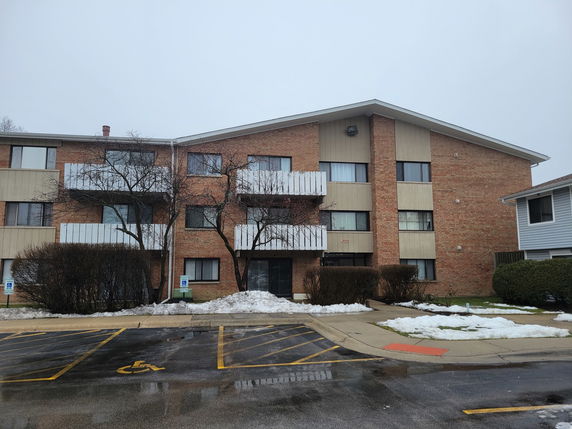 Front view of a three-story apartment building with brick exterior and balconies.